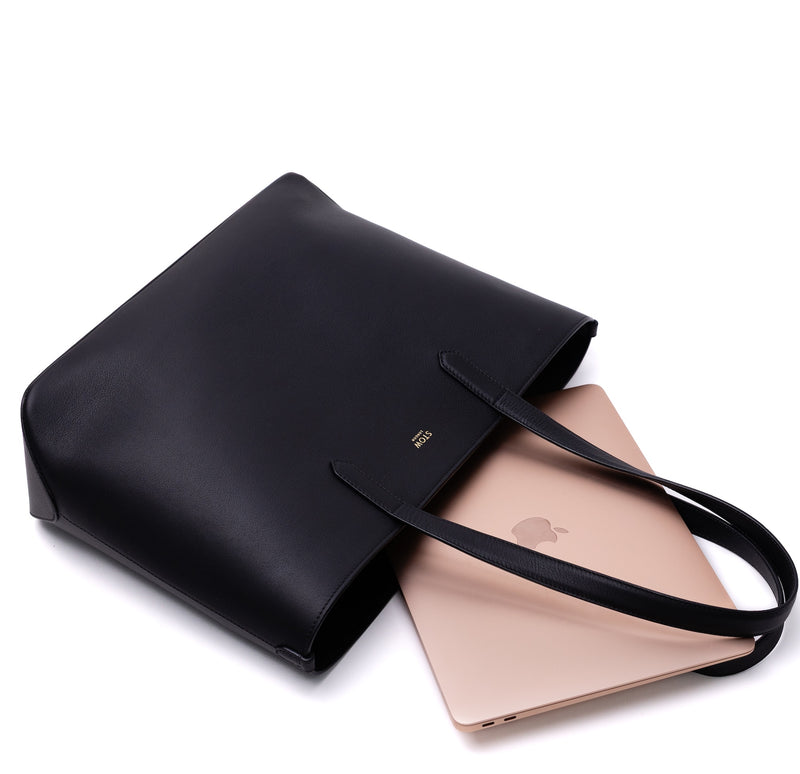 Stow London's Everyday Tote Bag in Black smooth leather with rose gold apple laptop on a light grey background featuring gold STOW logo